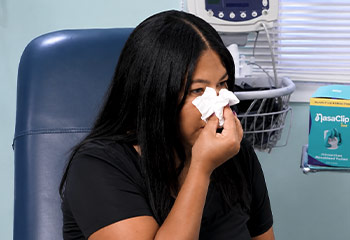 Woman holding her nose from a nosebleed with tissue